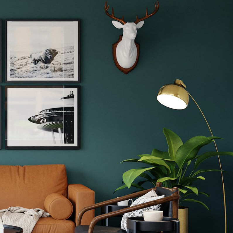 modern living room with green wall, dark orange couch, floor lamp, and wall décor