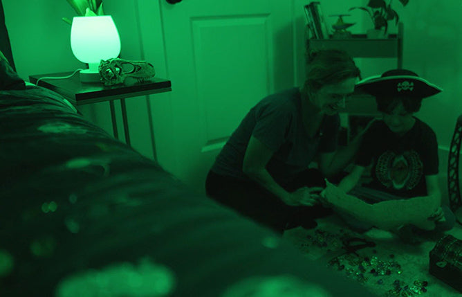 Person playing with a toy figure in a dimly lit room with green tint.