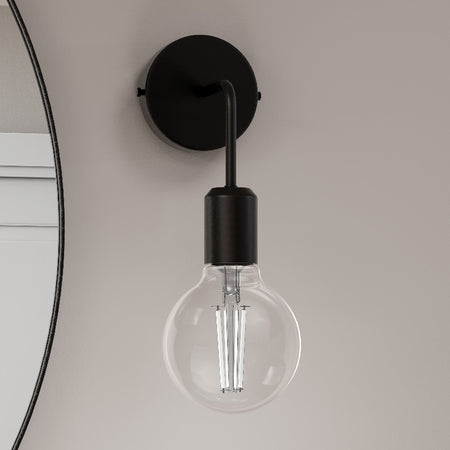 Black wall-mounted light fixture with a clear light bulb on a neutral background